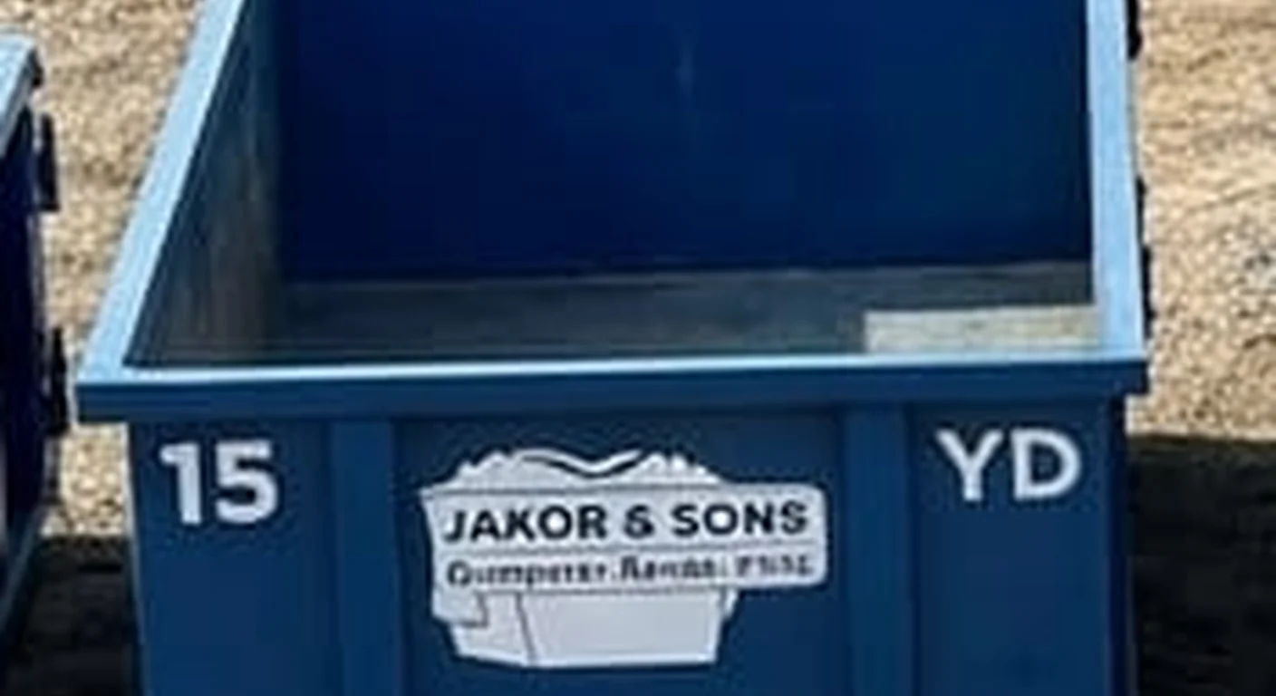 A clean, correctly-labeled 15 yard Jakob & Sons Dumpster Rental roll-off container staged at the company yard