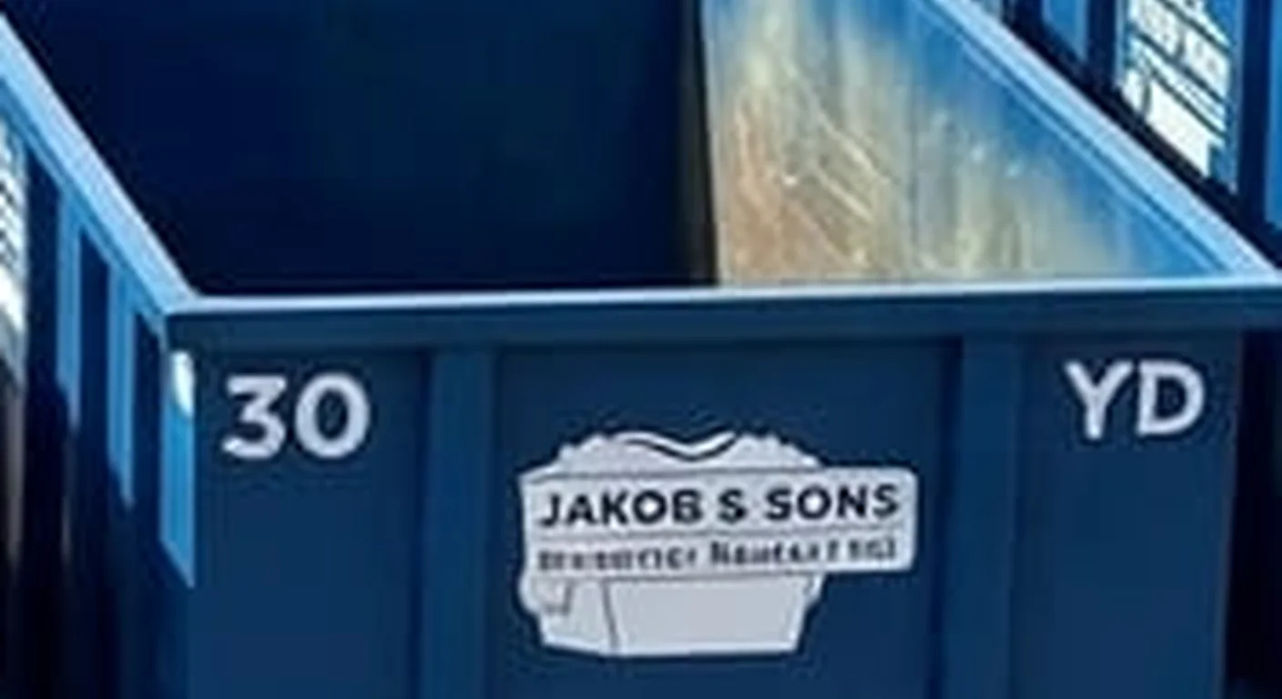 A clean, correctly-labeled 30 yard Jakob & Sons Dumpster Rental roll-off container staged at the company yard